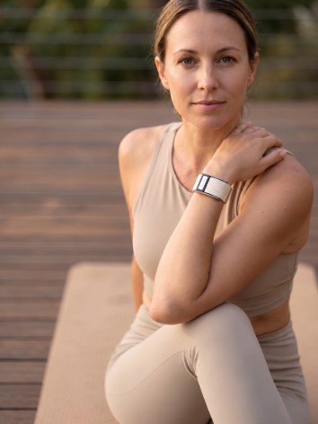 A woman on a yoga mat outdoors wearing a Thrive band
